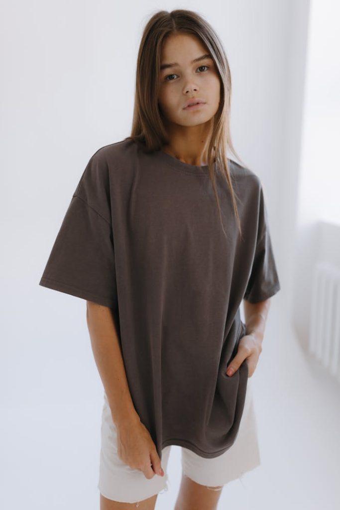 Young woman in oversized brown t-shirt, exuding casual and modern fashion vibes.